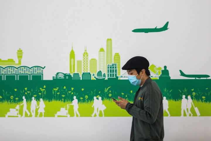 In this picture taken on April 4, 2020, a man wearing a face mask, amid concerns of the COVID-19 coronavirus, walks through the arrivals hall at Hong Kong International Airport. (Photo by DALE DE LA REY / AFP)