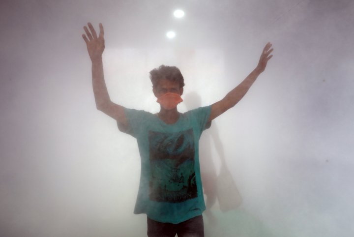 A man wearing a protective mask walks through a disinfectant tunnel installed in a market area during an extended nationwide lockdown to slow the spreading of coronavirus disease (COVID-19) in Kolkata, India, April 26, 2020.