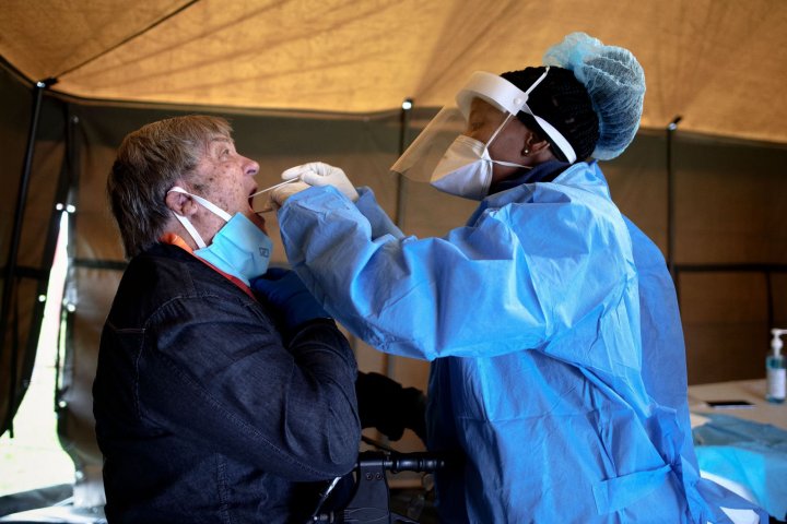An elderly man (L), a resident of Sophia Town, Johannesburg, opens his mouth to receive a testing swab for COVID-19 coronavirus at a screening and testing drive in a tent in the courtyard of Sophia Town Clinic, on April 28, 2020.